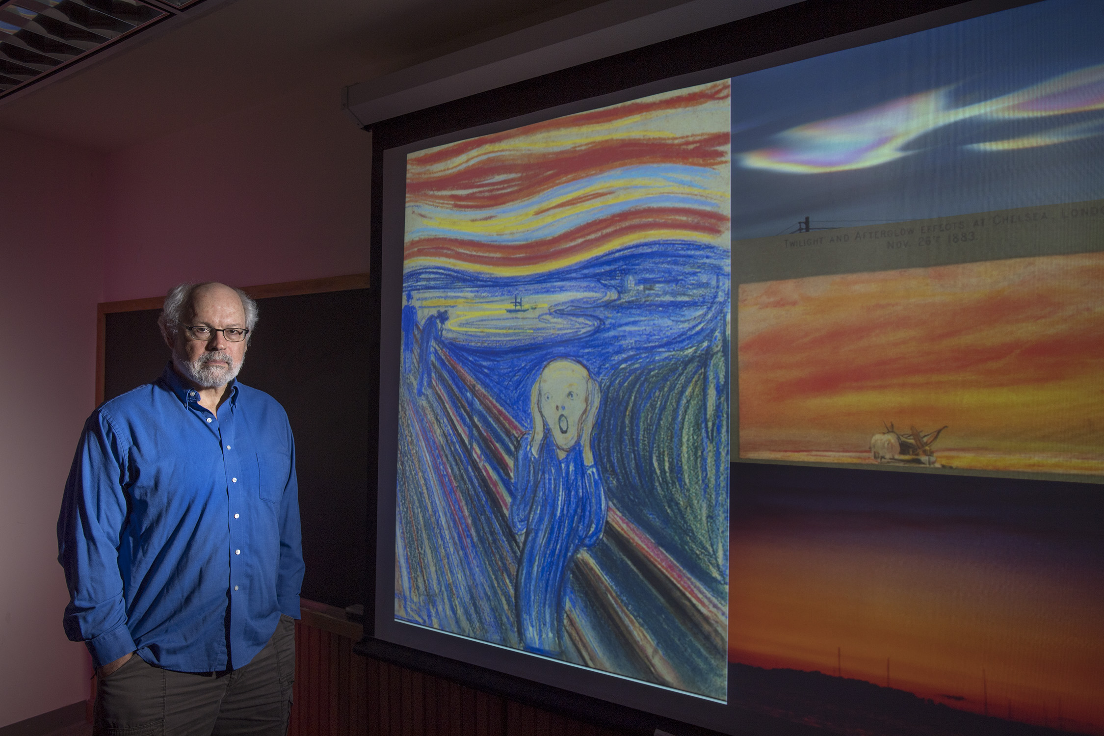 Rutgers Professor Alan Robock with an image of The Scream, an 1895 painting by Norwegian artist Edvard Munch. From top to bottom on the right are: a nacreous cloud over McMurdo Station in Antarctica in 2004; an 1883 drawing by William Ascroft showing the sky in London after the Krakatau eruption; and a 1982 volcanic sunset over Lake Mendota in Madison, Wisconsin, after the El Chichón eruption in Mexico. Photo: Nick Romanenko/Rutgers University