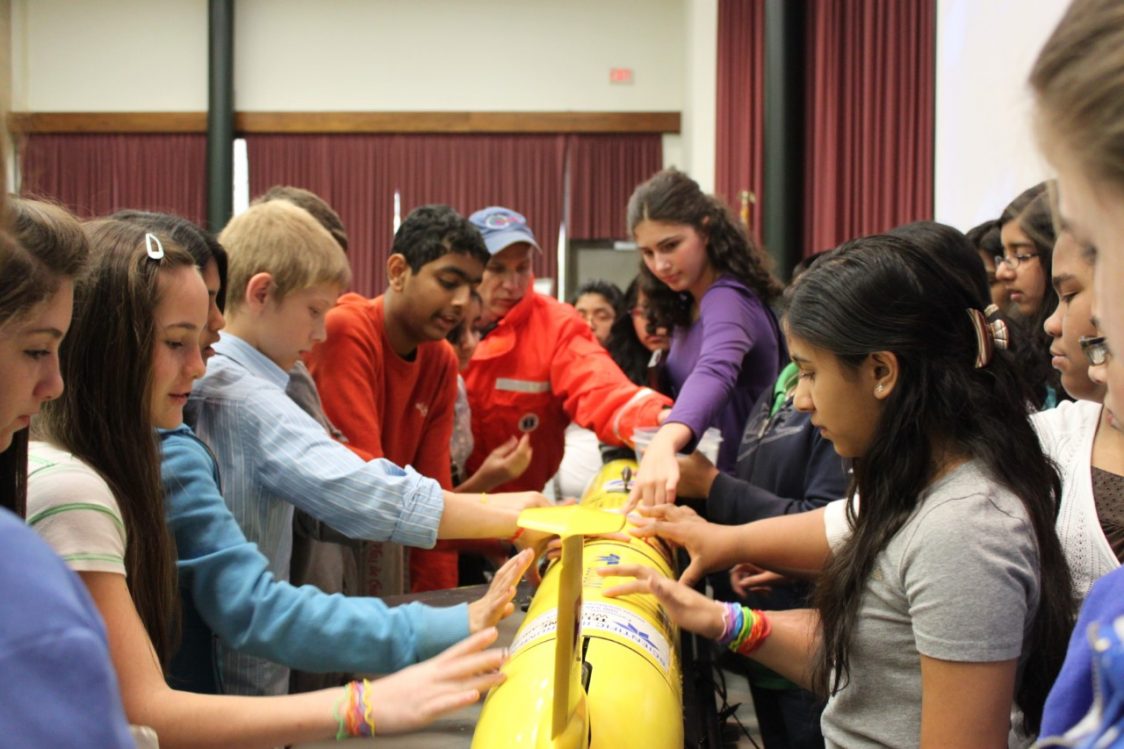 Distinguished Professor Scott Glenn (Center for Ocean Observing Leadership or COOL) discusses ocean gliders with a group of middle school students attending an Ocean Day community event.