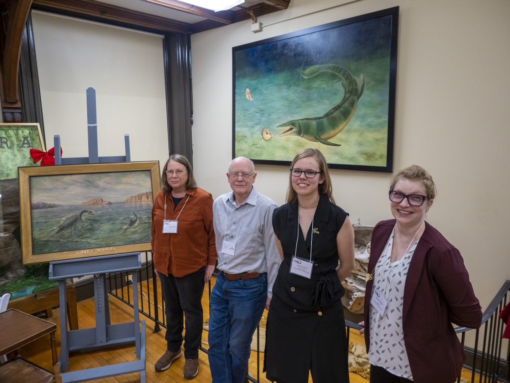 The Unveiling of the Restored Painting in the background. From Left to Right: Artist Jeanne Filler Scott, former Geology Museum Director Bill Selden, Graduate Student Amelia Zietlow from the American Museum of Natural History, and current Geology Museum Director Lauren Adamo